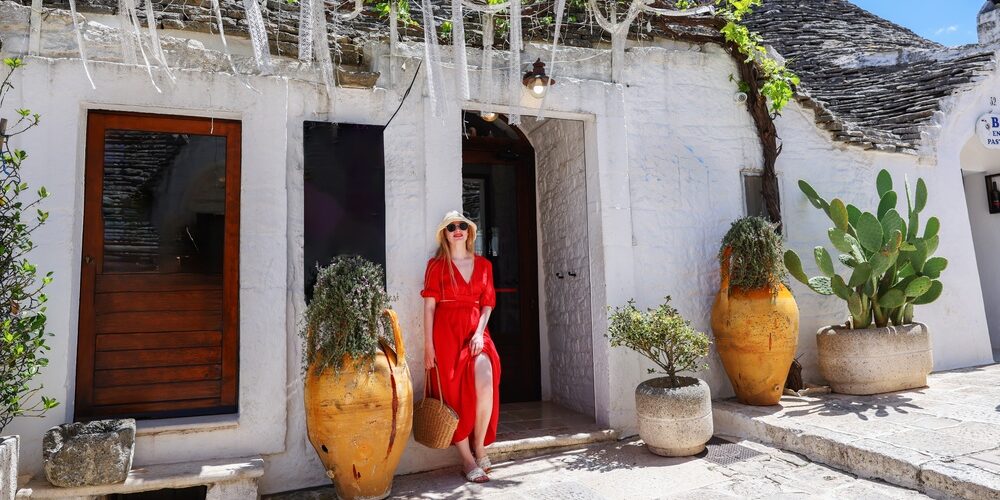 Beautiful,Tourist,In,Red,Dress,Exploring,Charming,Streets,Of,Alberobello,